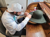 Student adding detail to the brim of a felt hat body during the course of a 5 day Hat Making Workshop